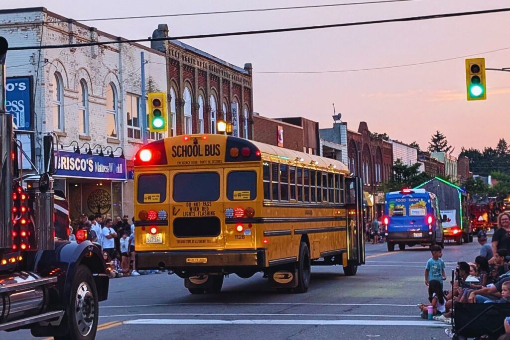 A Canadian orange school bus driving through a busy street